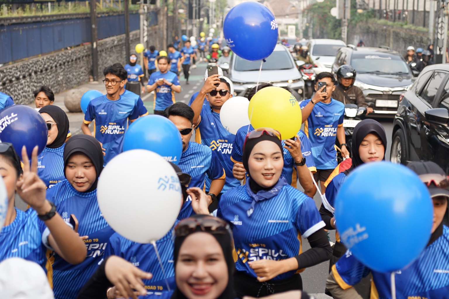 Peserta Road to Spill Run 2.0 berlari dengan jersey biru dan balon